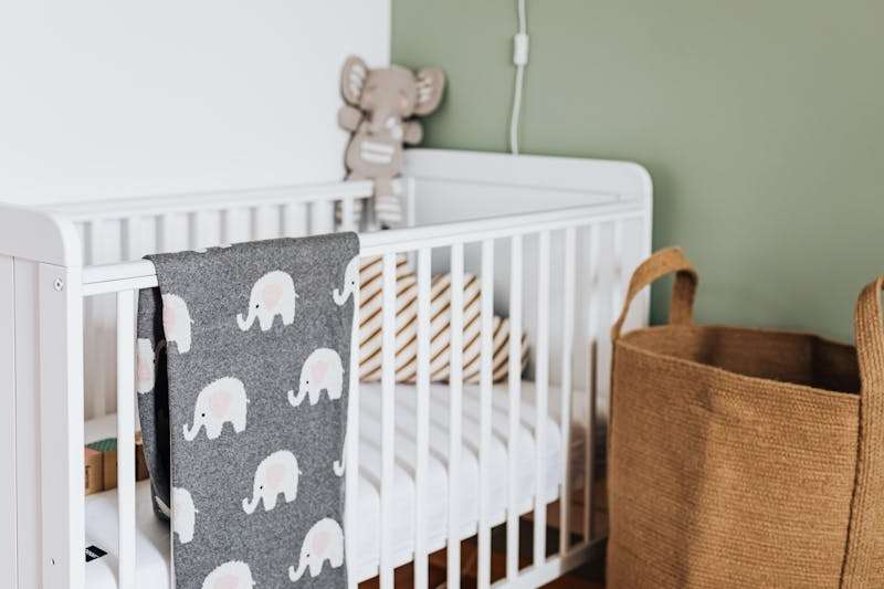 Minimal nursery with a white wooden cot, woven basket, and soft blanket